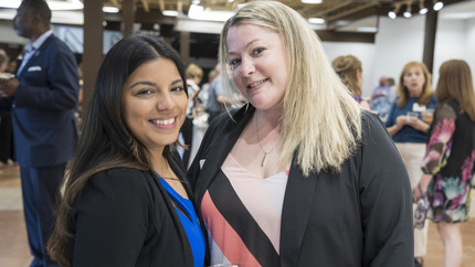 Two women standing next to each other looking at the camera and smiling.