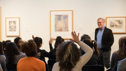 Members of audience face a male speaker who is smiling.